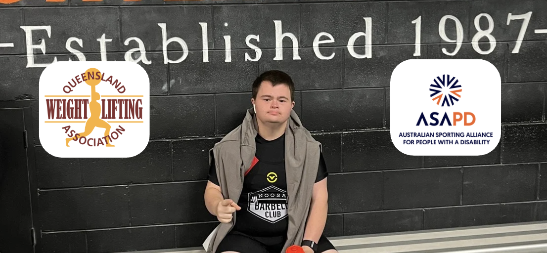 A person sits on a bench in front of a wall with large, bold orange and white text that says "WEIGHTLIFTING" and "Established 1987-". The person is wearing a black shirt with "Noosa Barbell Club" on it and has a jacket draped over their shoulders. They are holding an orange water bottle and gesturing with one hand. On the left and right sides of the image are the Queensland Weightlifting Association and ASAPD logos.